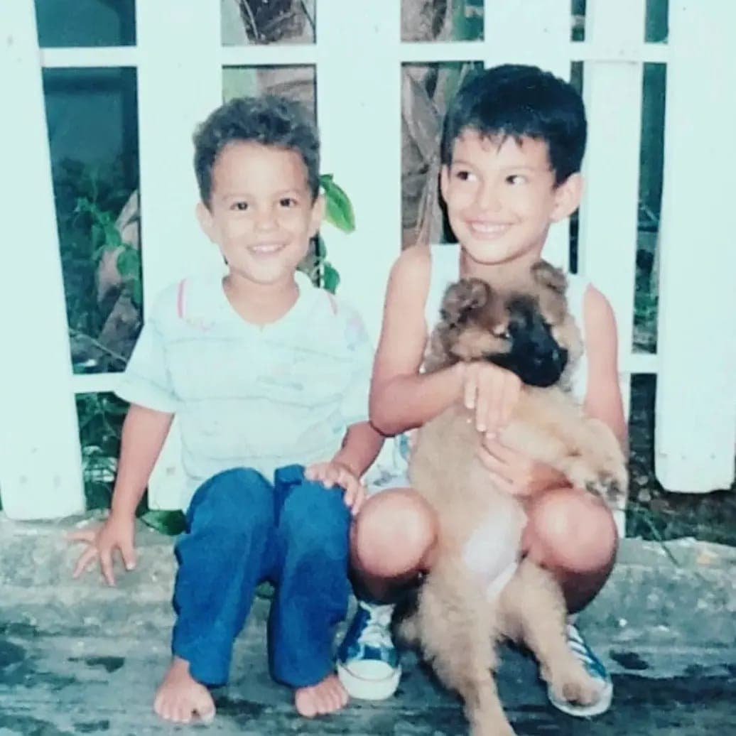 Ulises de chico sosteniendo a Tico cuando era un cachorro, junto a su hermano Samuel